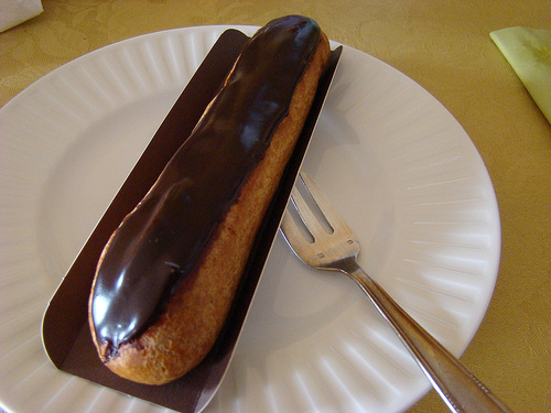eclair on white paper plate with fork