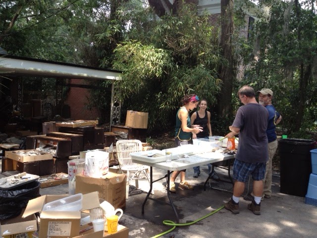 Valeria, Ashley, John, and Roger gathered around a table in Harry's driveway with specimens in boxes piled all around