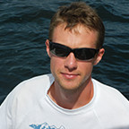 man with white tshirt and sunglasses with water in the background