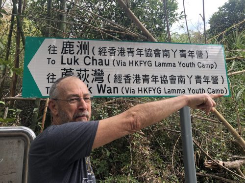 Gustav standing under a sign and pointing the wrong way