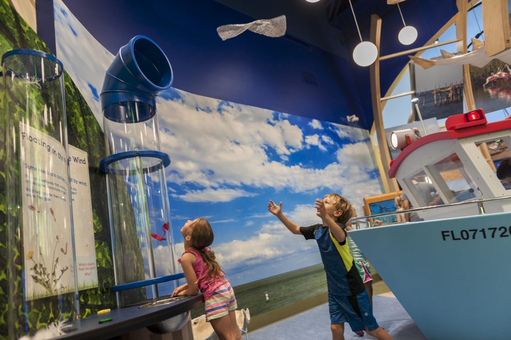 Children use the wind tunnel in the Discovery Zone exhibit.