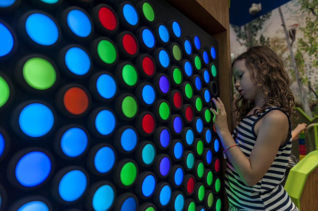 A child plays with the multicolored lights in the Discovery Zone exhibit.