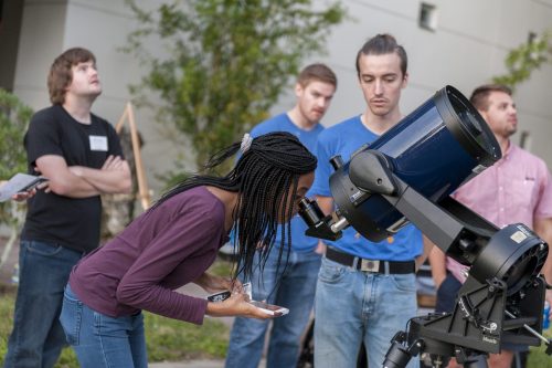 A girl looks through a high-powered telescope to look at planets during the day. ©Florida Museum photo by Kristen Grace
