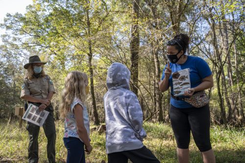 Children, teacher and park ranger standing in the woods