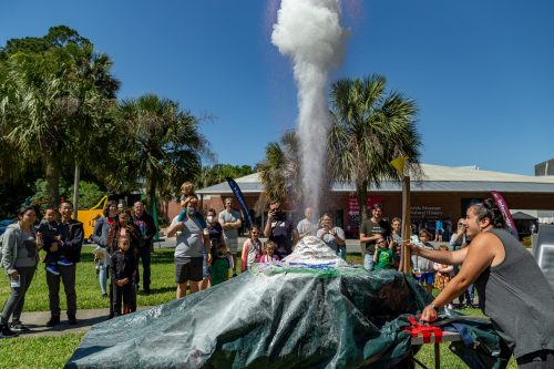 A group of people watch a volcano demonstration 