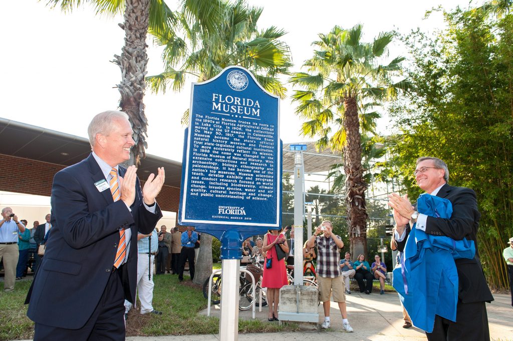 Doug Jones and Kent Fuchs clap after the unveiling for the new Florida Museum sign