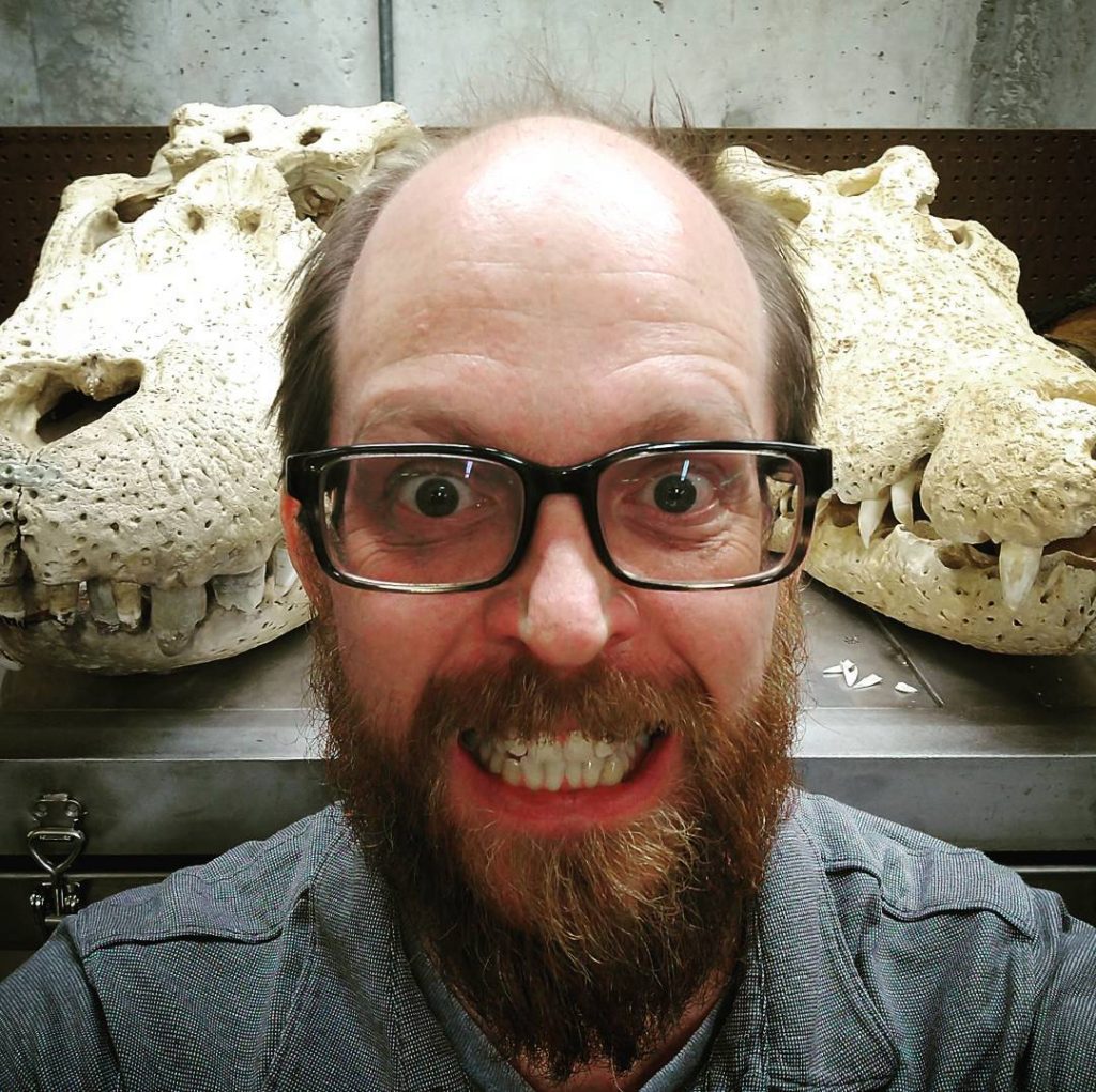 Andy selfie in front of two gator skulls, all showing teeth