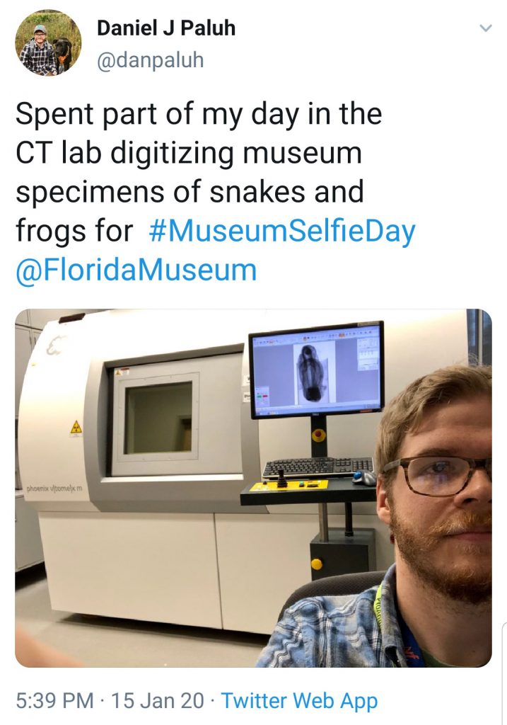 man taking selfie in front of large scientific equipment