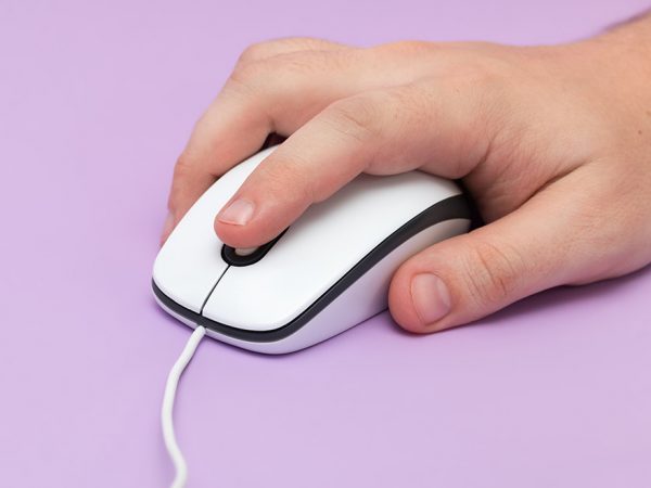 a hand holding a older style mouse with a cord