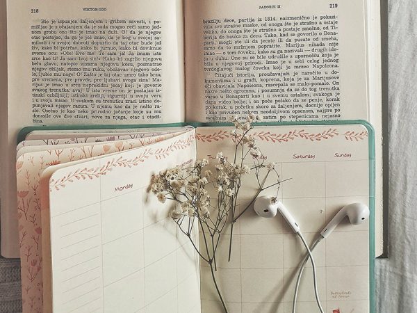 earbuds and a sprig of flowers on an open notebook