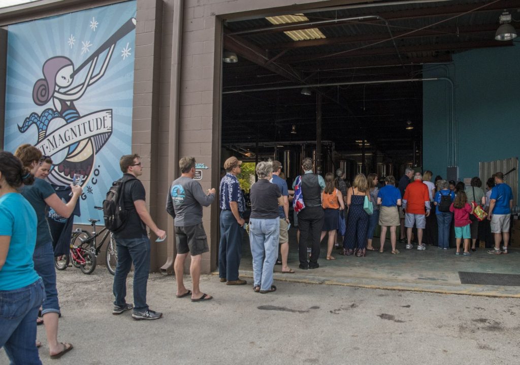 a line of people in the open bay doors of a brewery