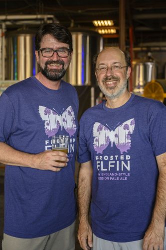 two people in butterfly beer tshirts standing in a brewery