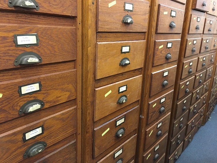 wood storage cabinets with many drawers each with a small label