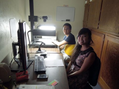 two researchers sitting at a desk with a computer and a light-table and camera