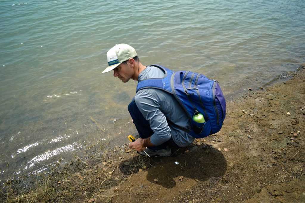 Jason of the GABI RET program examines the stratigraphy along the shores of Lake Alajuela.