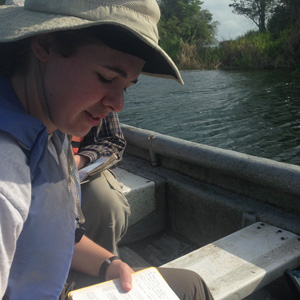 Sophie Westacott writing in her field notebook on Lake Bayano. Photo by S. Sanchez.