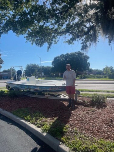 Sad man standing next to crashed boat and trailer by road