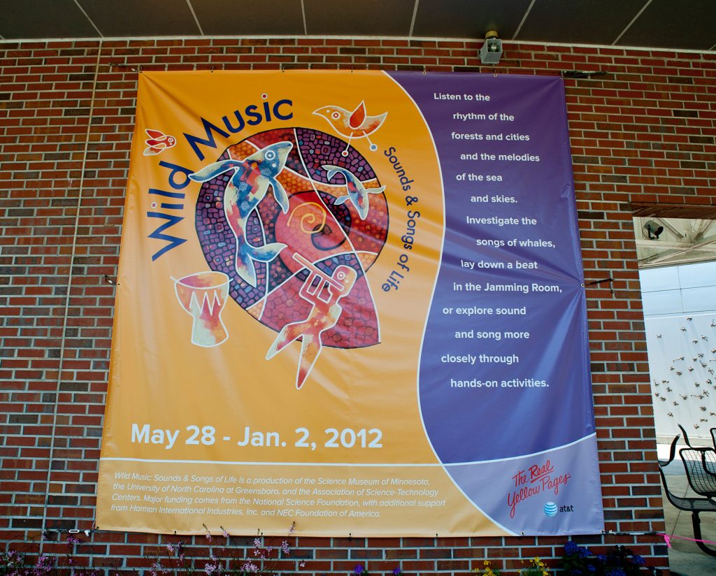 Large banner for the Wild Music exhibit hung on the outside wall of the Florida Museum