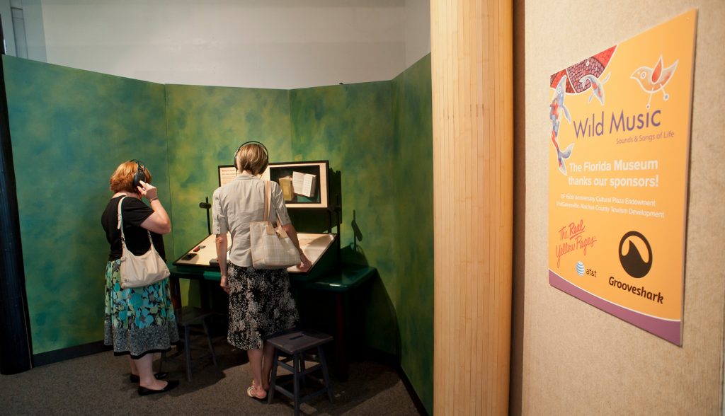 two visitors use headphones to listen to exhibit display