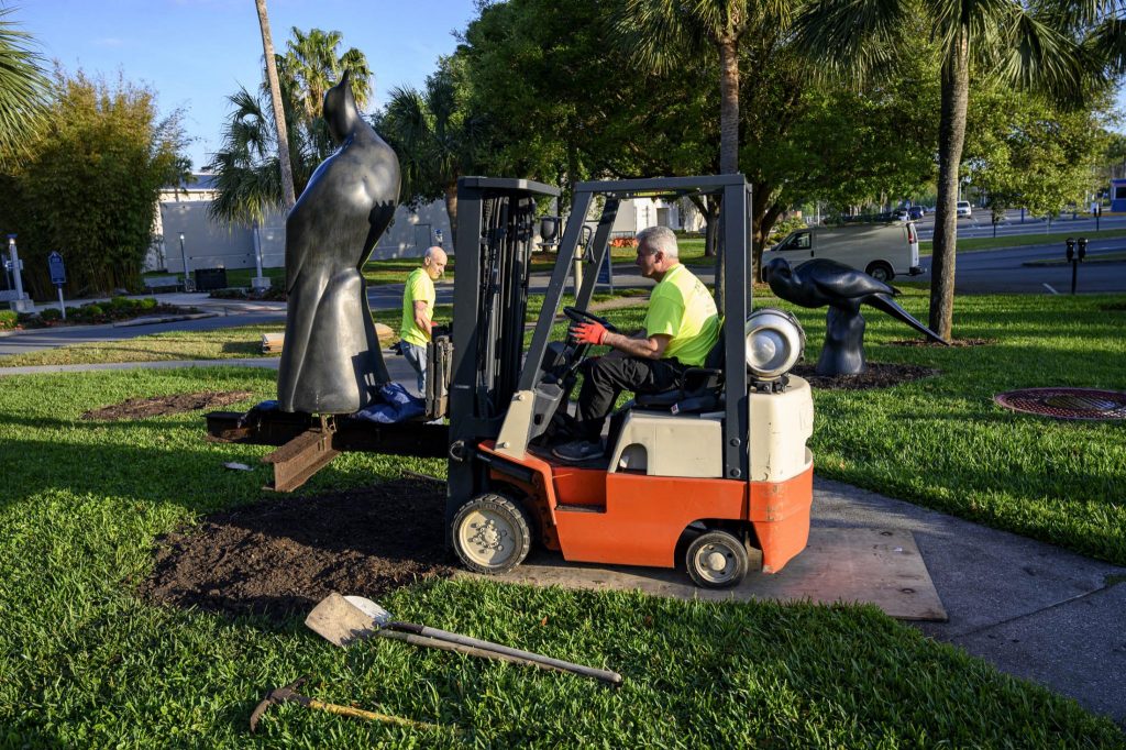 a man in a forklift moving a large statue off the lawn