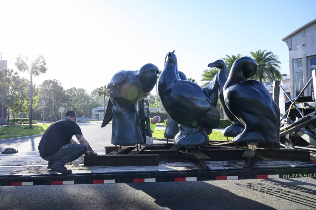 a man secures large bird statues in a flatbed trailer