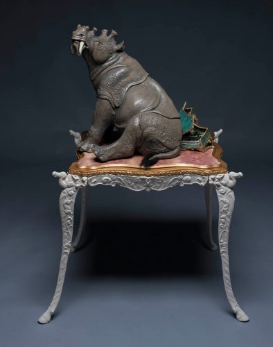 sculpture of a Uintatherium sitting on a broked harpsichord