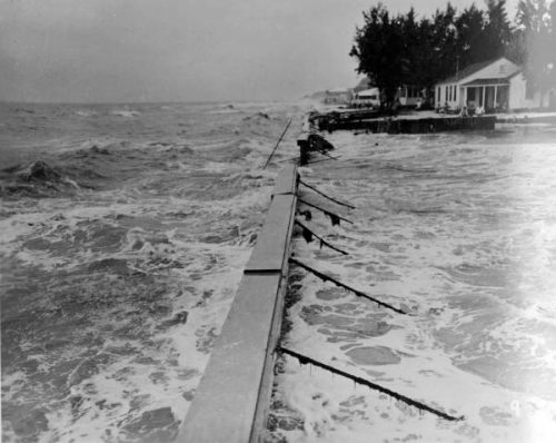 black and white photo of concrete seawall with water close to the top of both sides. 