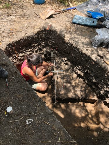 a researcher in a square hole taking measurements