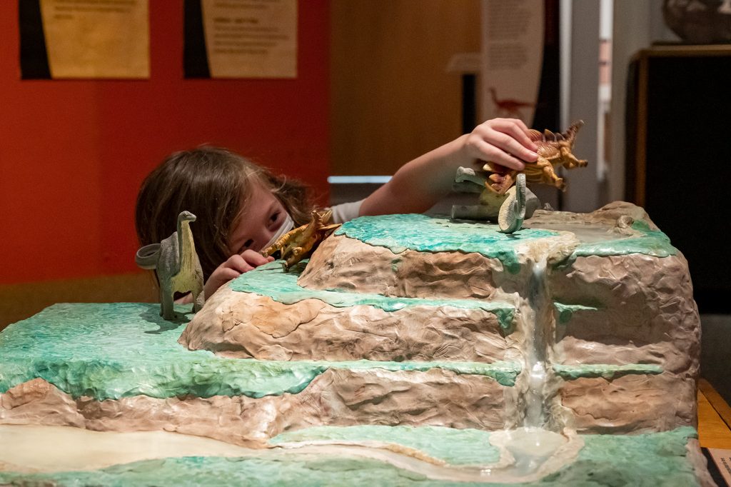 young child plays with dinosaurs toys in the interactive exhibits