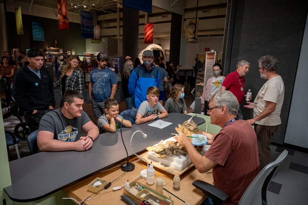 Scientists working on a fossil specimen and speaking with many exhibit visitors