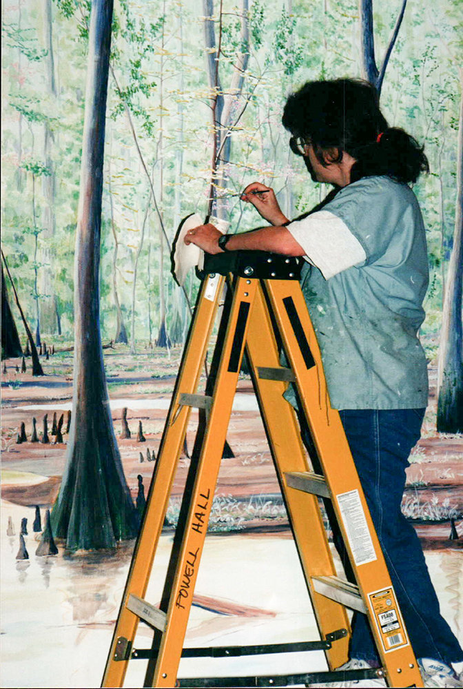 woman on ladder painting a mural