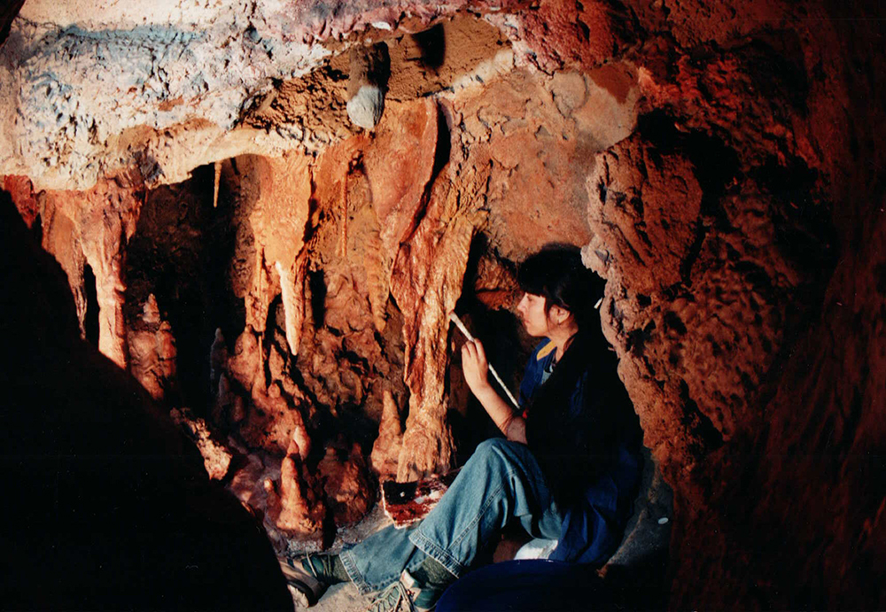 Woman painting a cave depiction