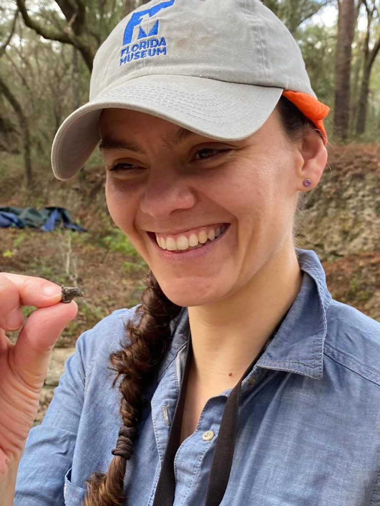 volunteer smiling holding small fossil