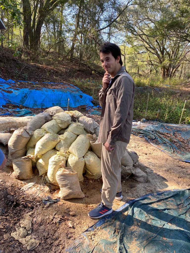 volunteer standing next to large pile of sand bags