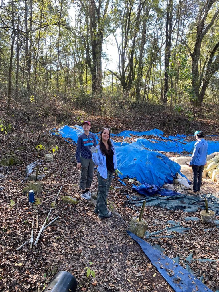 volunteers next to site covered in blue tarps and leaves