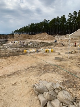 dig site with tent and many yellow buckets