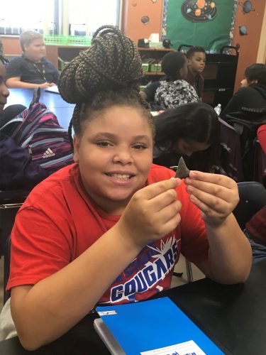 student holds fossil shark tooth