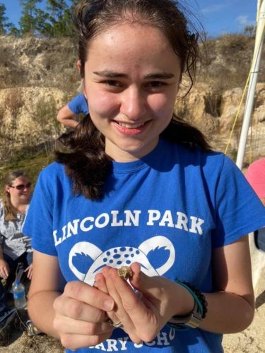 teacher holds fossil horse tooth