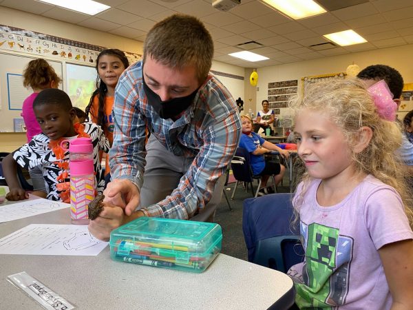 alan ivory showing first grade student a frog during a classroom visit