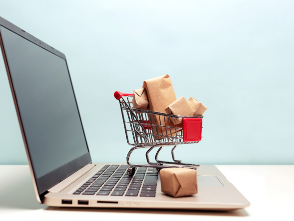 Image of a small shopping cart full of boxes sitting on top of an open laptop
