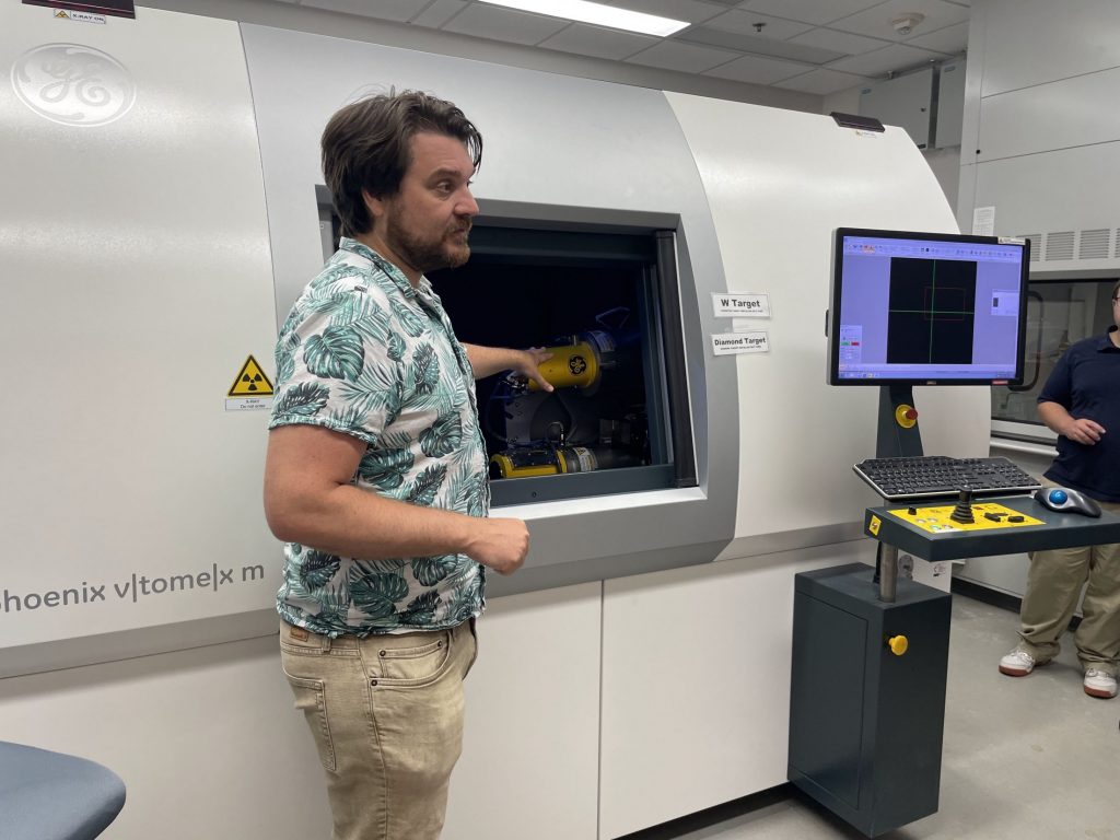 a scientist shows teachers how to use a CT scanner