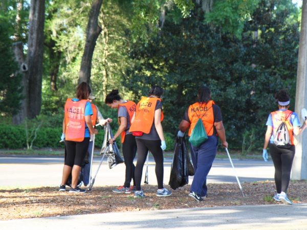 group of volunteers in orange vests picking up litter