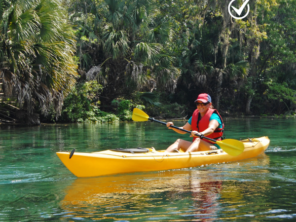A person smiles while kayaking on a river.