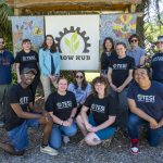 students and staff posing in front of a sign