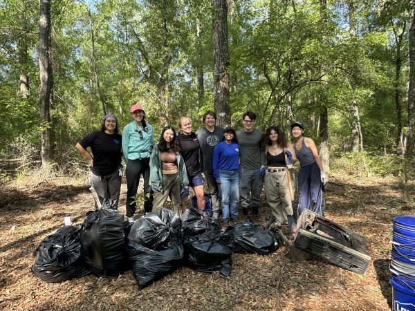 Group photo of the TESI team and students in front of the trash bags of the debris they picked up at the cleanup.