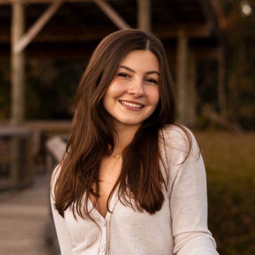 Elle Henson smiling while standing on a boardwalk at La Chua trail overlooking Paynes Prairie