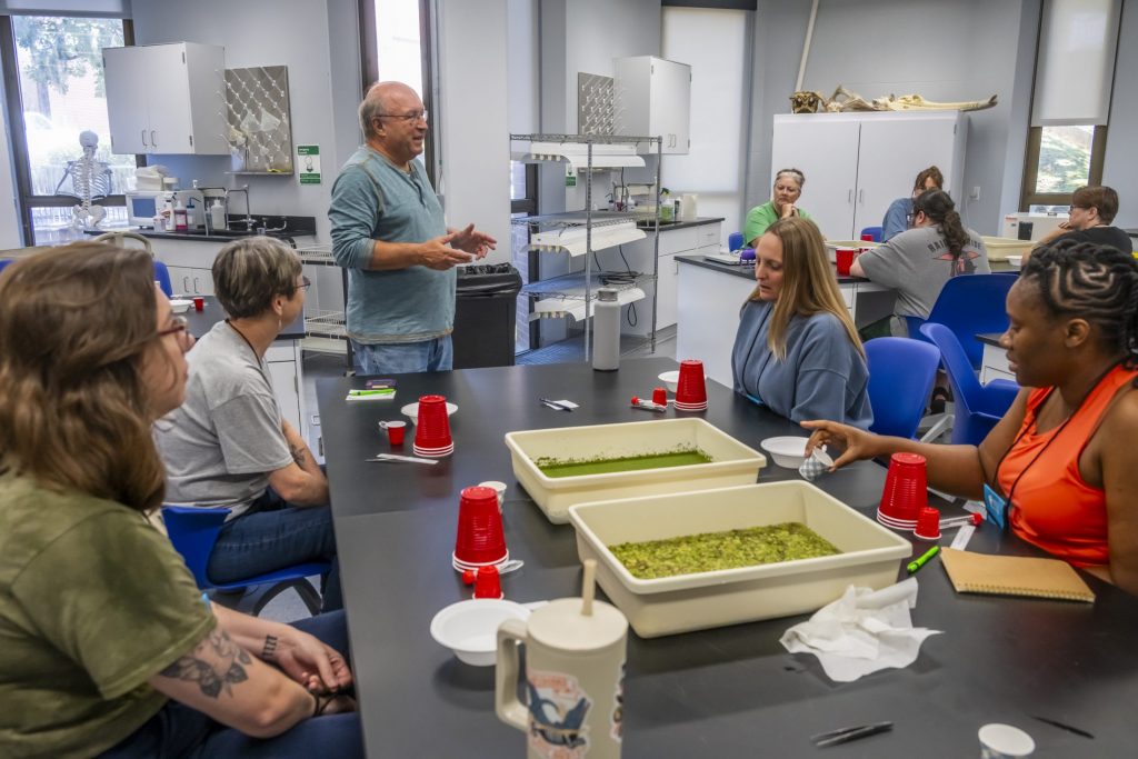 scientist talking to teachers who are sitting at lab benches