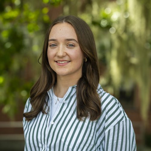 Natalie smiling in front of greenery for her headshot.