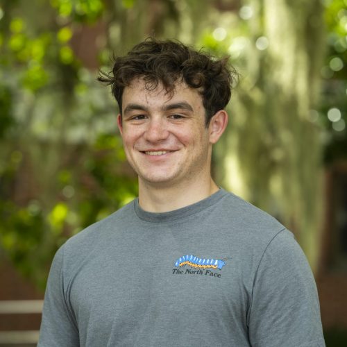 Drew standing in front of trees outside Dickinson Hall smiling for headshot.