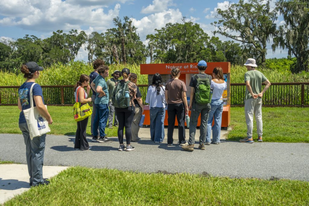 Fellows standing in front of an educational display at the Ocala Recharge Wetland, with Matthew Stanley explaining the purpose of the park.